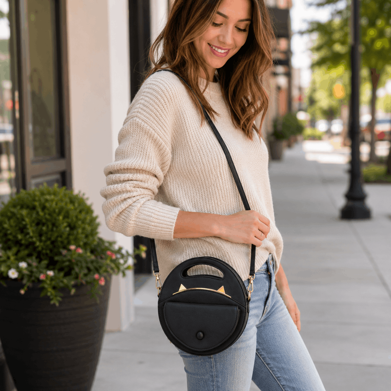 Woman carrying a black cat crossbody bag while walking outdoors