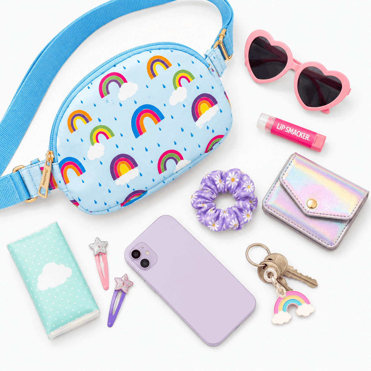 Flat lay of the April Showers Belt Bag with everyday essentials including a phone, sunglasses, wallet, lip balm, notebook, keys, hair accessories, and scrunchie.