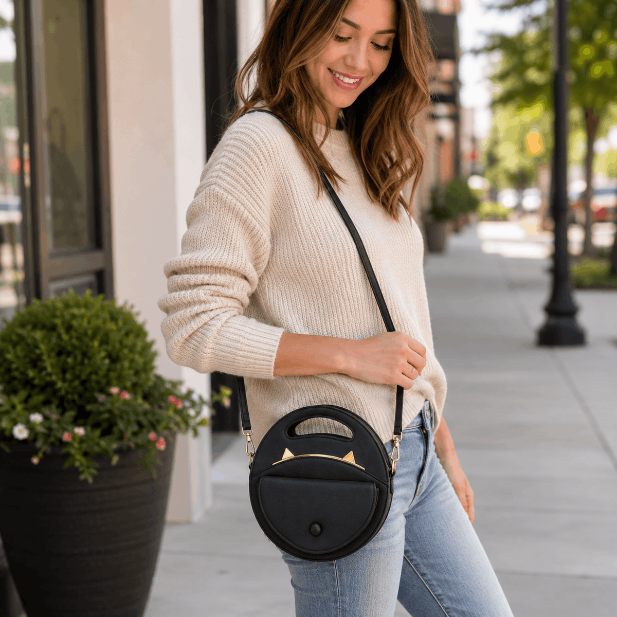 Woman carrying a black cat crossbody bag while walking outdoors