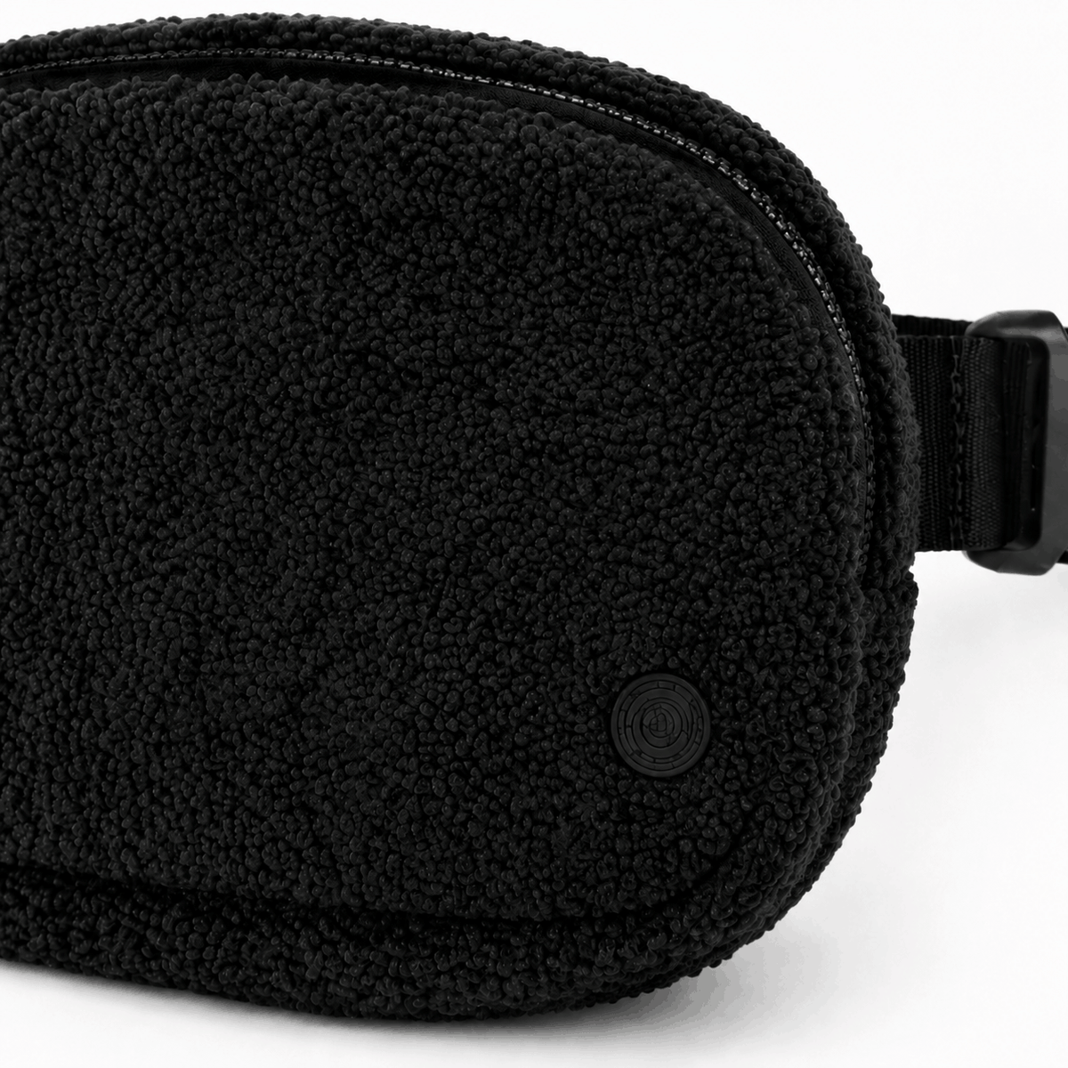 Close-up of the black fleece texture, zipper, stitching, and tonal emblem