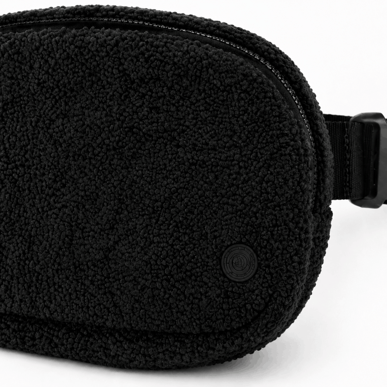 Close-up of the black fleece texture, zipper, stitching, and tonal emblem