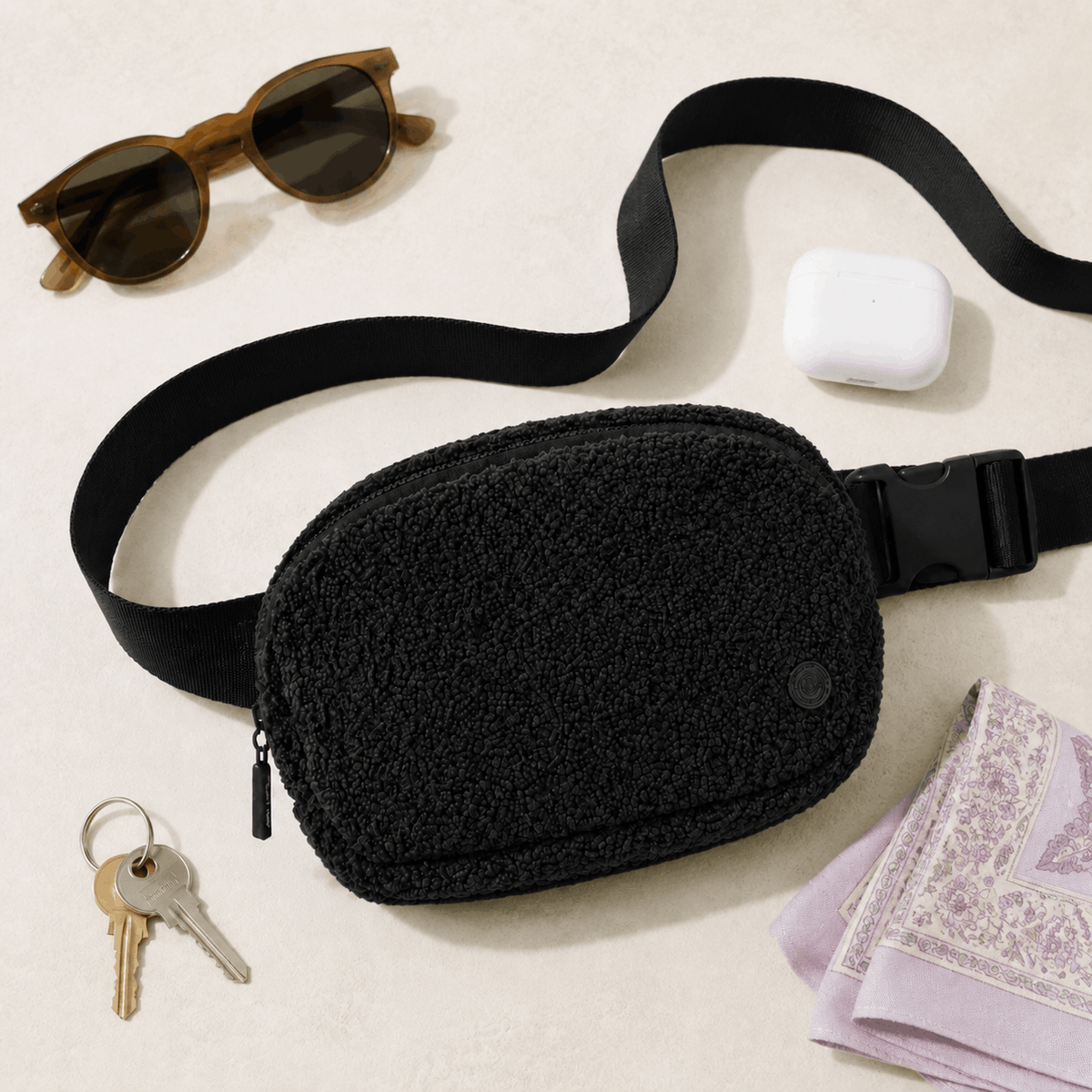 Black Fleece Belt Bag arranged with everyday essentials in a flat lay