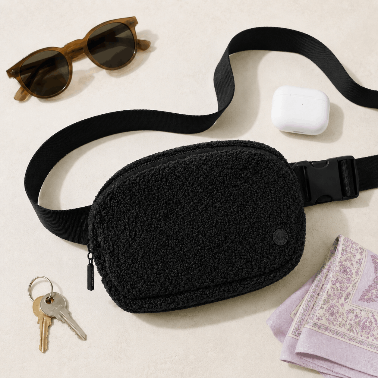 Black Fleece Belt Bag arranged with everyday essentials in a flat lay