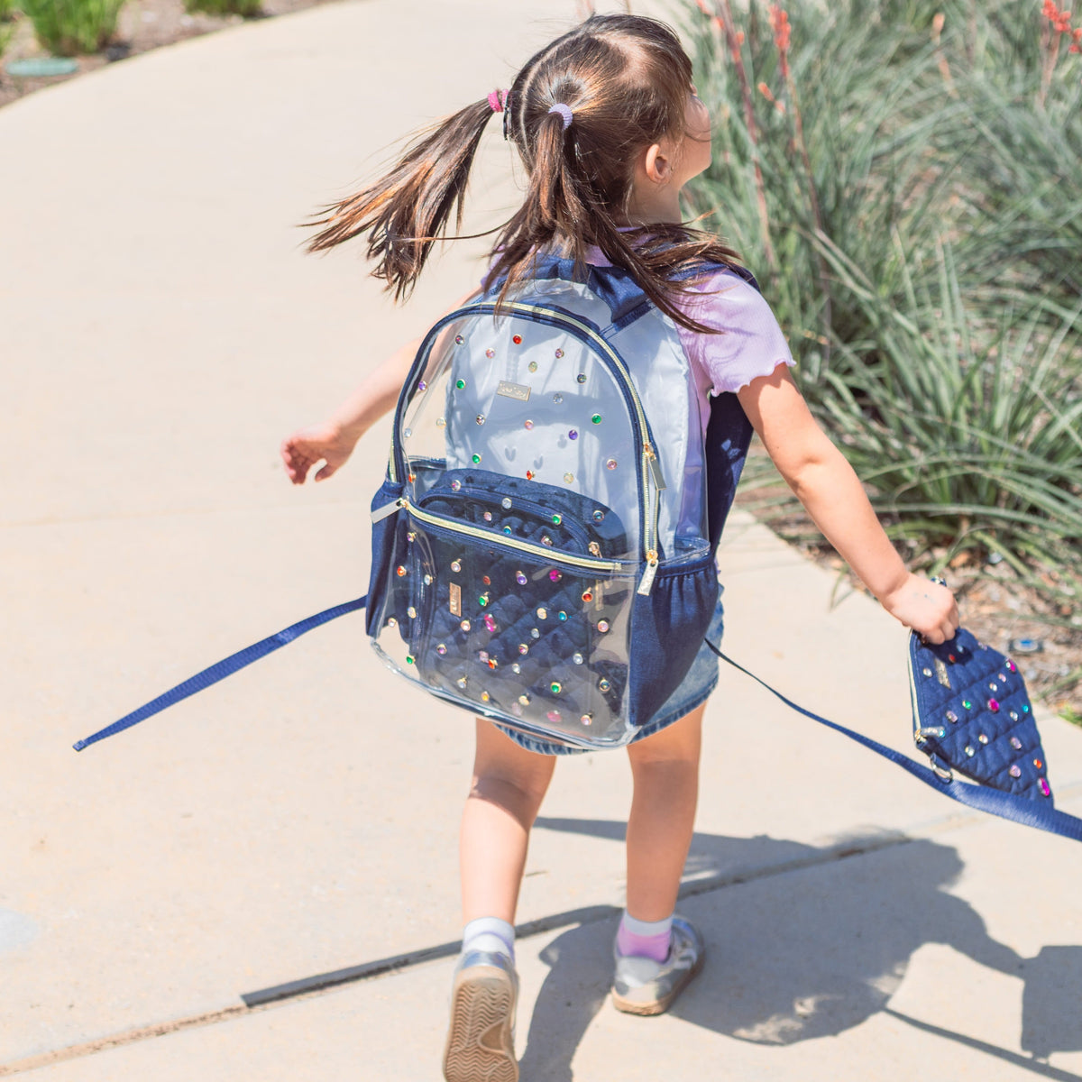 Child wearing the Clear Denim and Gems Backpack outdoors.
