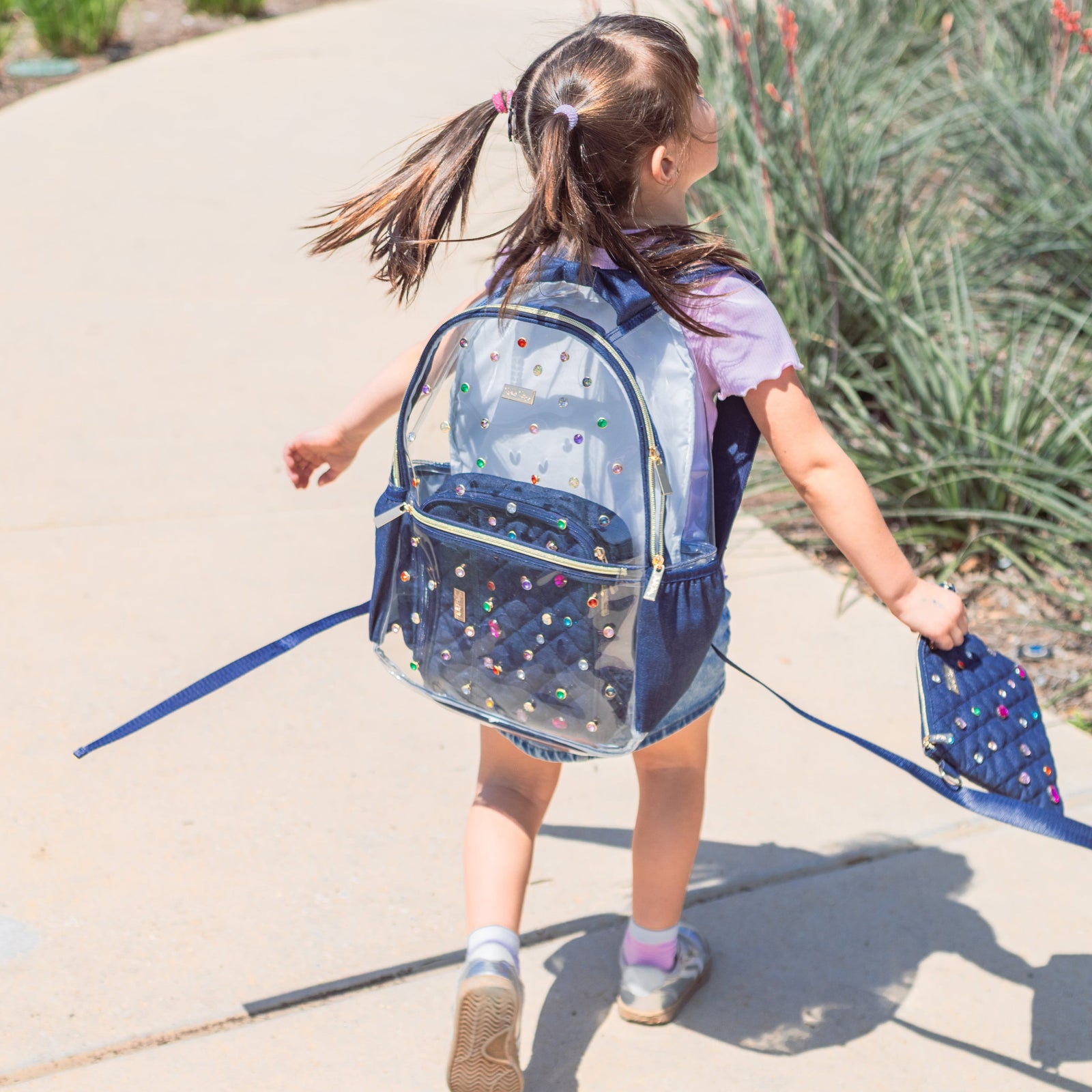 Child wearing the Clear Denim and Gems Backpack outdoors.