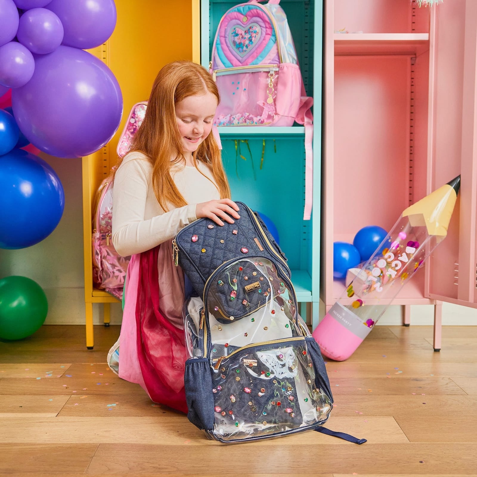 Child packing the Clear Denim and Gems Backpack in a colorful school setting.