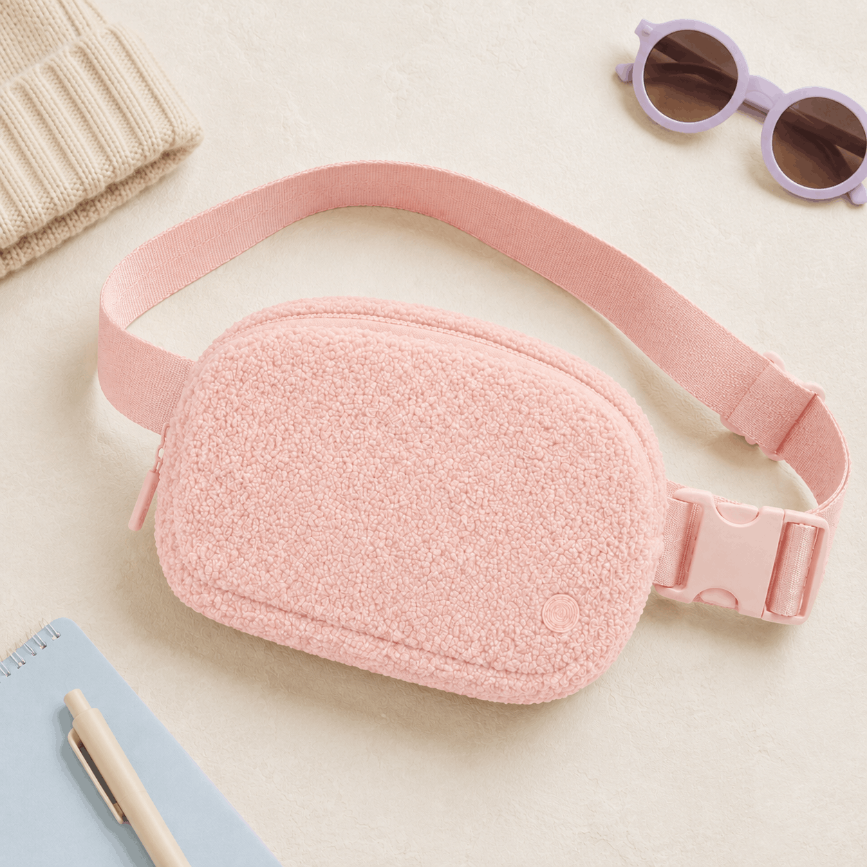 Light pink fleece belt bag flat lay with coordinated pastel accessories