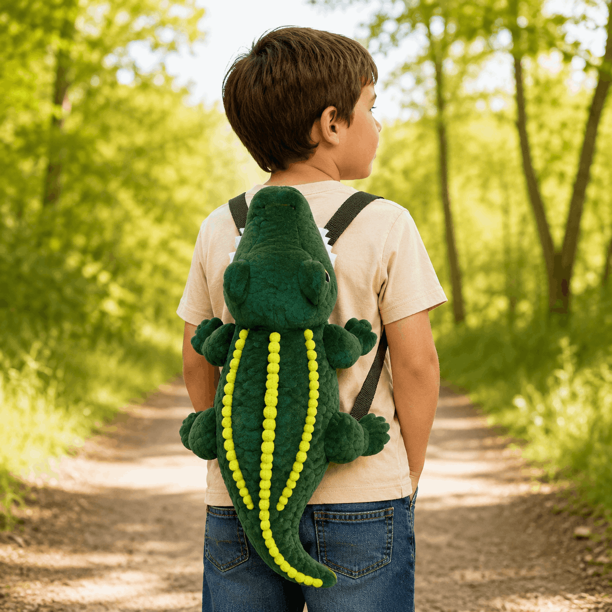 Child wearing the Plush Alligator Backpack outdoors, showing how the novelty backpack looks when worn from the back.
