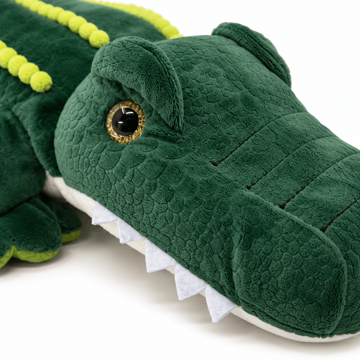 Close-up of the Plush Alligator Backpack showing the embroidered eye, textured plush fabric, and soft felt teeth.