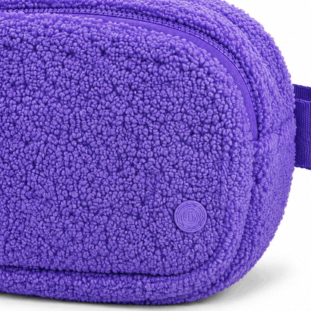 Close-up of purple fleece texture, zipper, stitching, and circular emblem