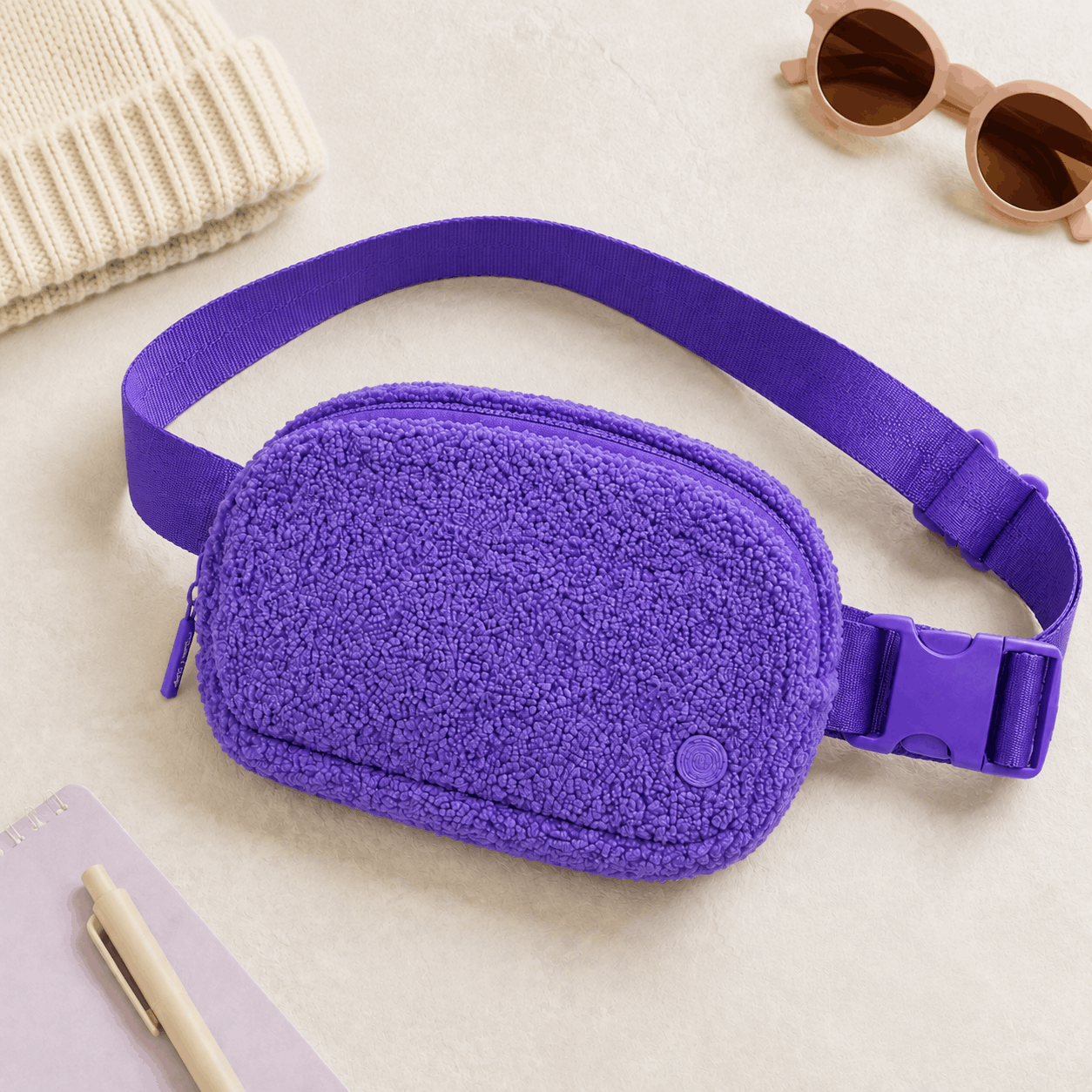Purple fleece belt bag flat lay with coordinated pastel accessories